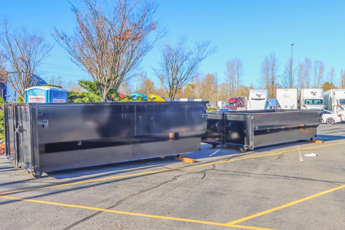 Professional dumpster rental service with roll-off container on residential driveway in Raymond